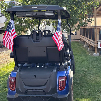 Customer's blue golf cart from behind with an American flag strapped to each rear roof post.