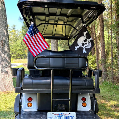 Customer's lifted golf cart from behind with an American Flag and a Jolly Roger strapped to the rear roof posts.