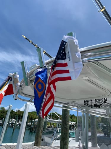 Customer's Bahamian Courtesy Flag mounted on a boat alongside an American flag at a sunny dock.