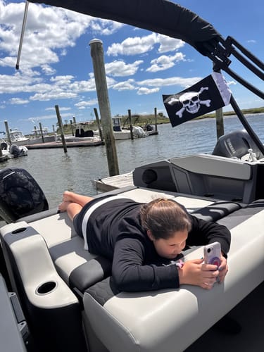 Jolly Roger flag flying from the back of a boat while a person relaxes on a lounge seat.
