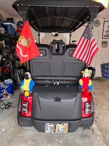 United States Marine Corps flag mounted on the back of a golf cart alongside an American flag.
