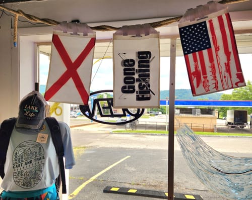 Store window display featuring the Gone Fishing flag hanging alongside other flags.