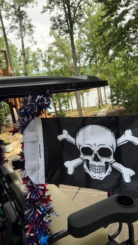Black Jolly Roger flag hanging from the side of a decorated golf cart.