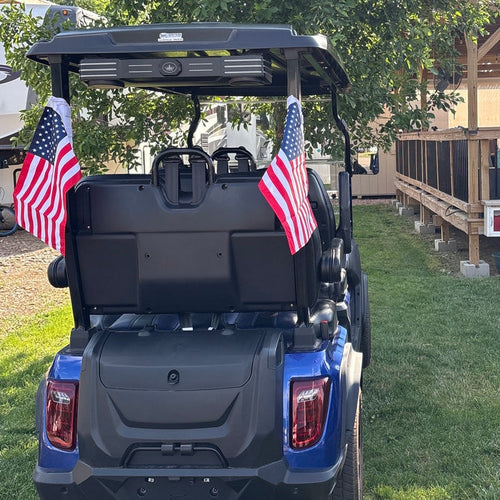 Customer's blue golf cart from behind with an American flag strapped to each rear roof post.