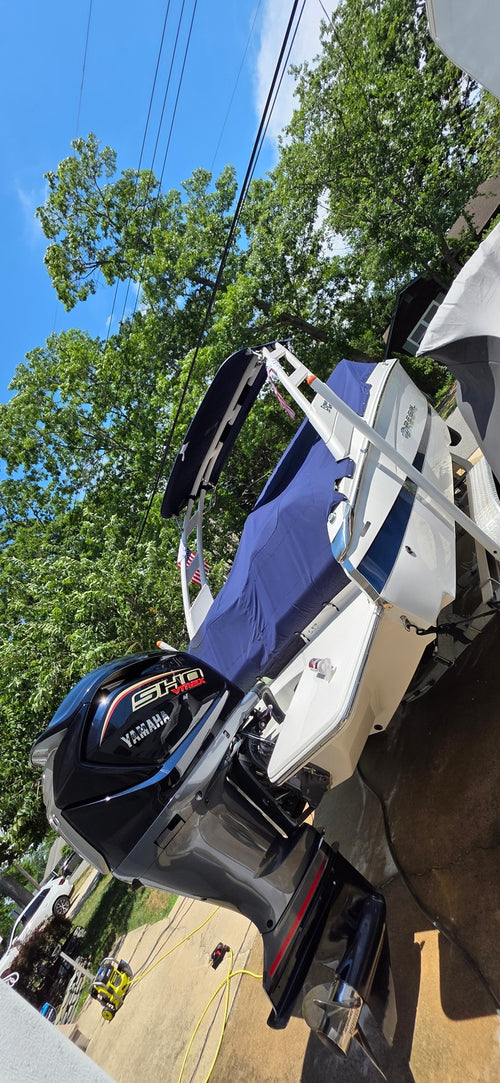 Customer's boat with a blue power top and outboard engine in a sunny outdoor setting.